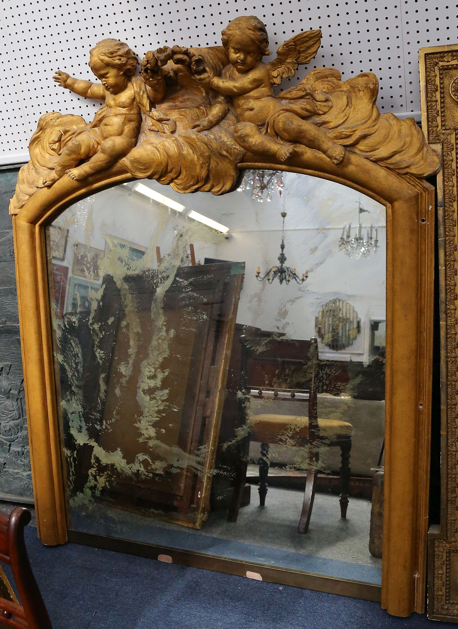 A large gilt overmantle mirror with an arched top surmounted with cherubs. 170 by 140 wide.