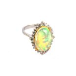 An opal and diamond cluster ring, The oval-cut opal, within a brilliant-cut diamond surround,