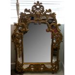 A large carved and pierced gilt wall mirror in the rococco manner. Height 144 Width 99 cms