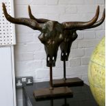 Pair of bronzed metal models of Buffalo skulls on ebonised stands 40 cms H