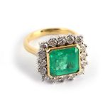 An emerald and diamond cluster ring, The collet-set square step-cut emerald, within a surround of