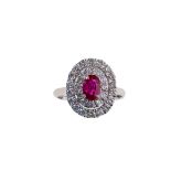 A ruby and diamond cluster ring The oval-cut ruby, in an 18 carat white gold four-claw setting,