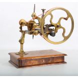 A19TH CENTURY BRASS CLOCK / WATCH MAKERS TOOLS (LATHE / MANDREL) raised on a mahogany base fitted