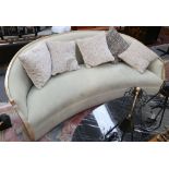 A modern design moon shaped sofa, upholstered in pale sage green, having gilded border, designed