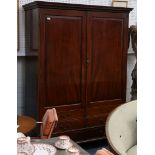 A George III style, mahogany wardrobe modelled as a linen press, with panelled dummy drawer front on