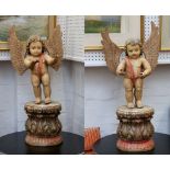 A pair of decorative carved wood putti, with glass eyes on acanthus bases, 87cm.