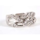 An 18ct white gold contemporary dress ring, the open work band with ten rub-over set diamonds.