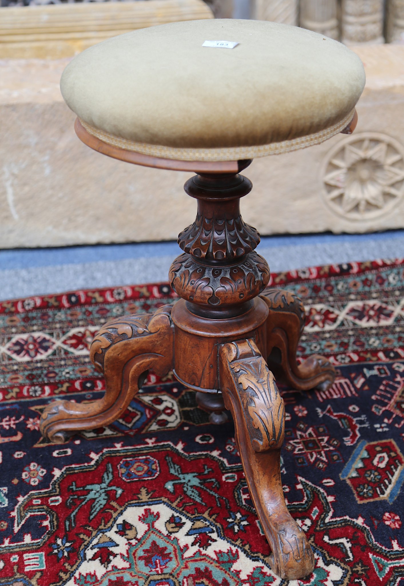 A Victorian carved walnut adjustable tripod piano stool.