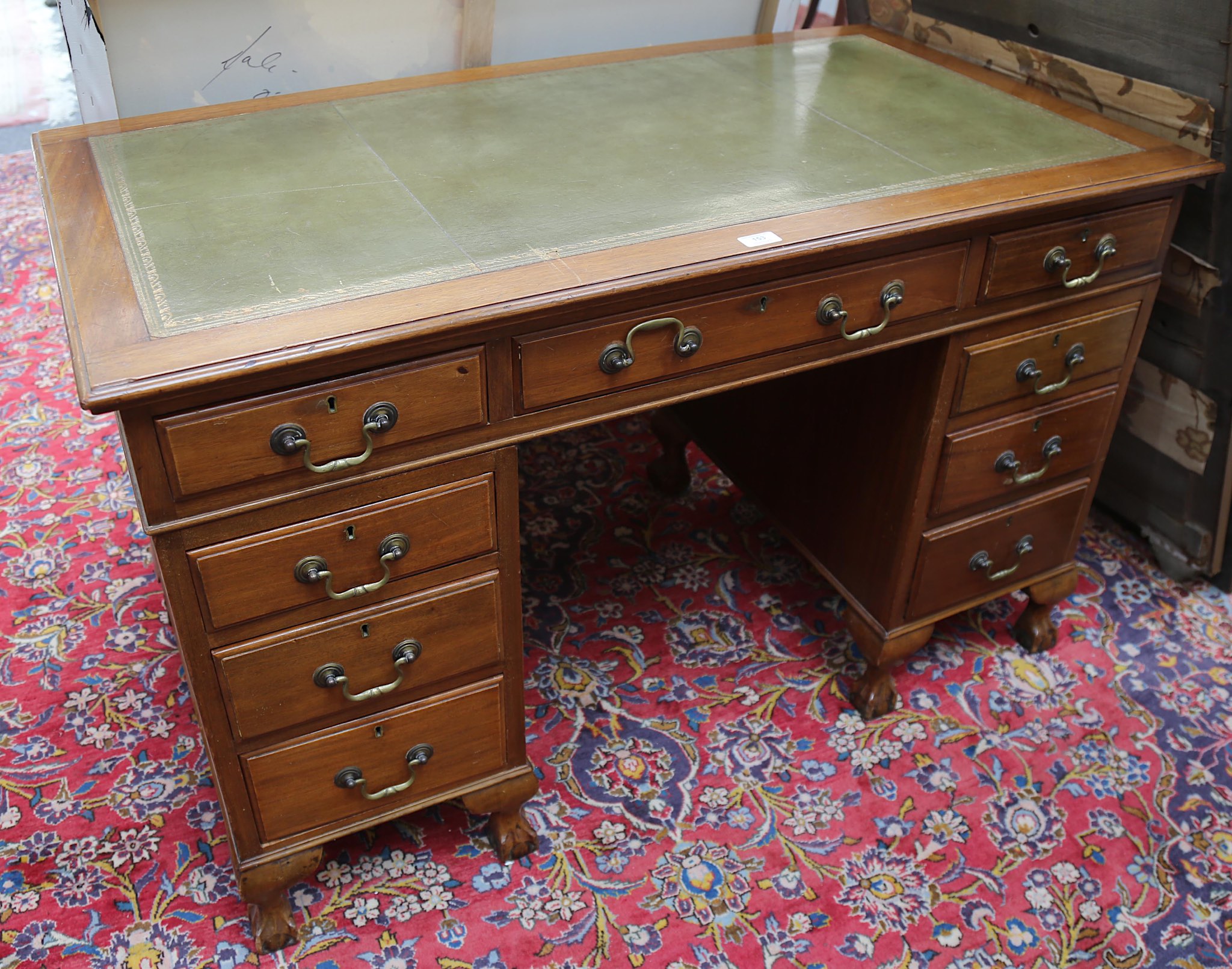 A 1920's mahogany pedestal desk, with green leather inset top over nine drawers, on claw and ball