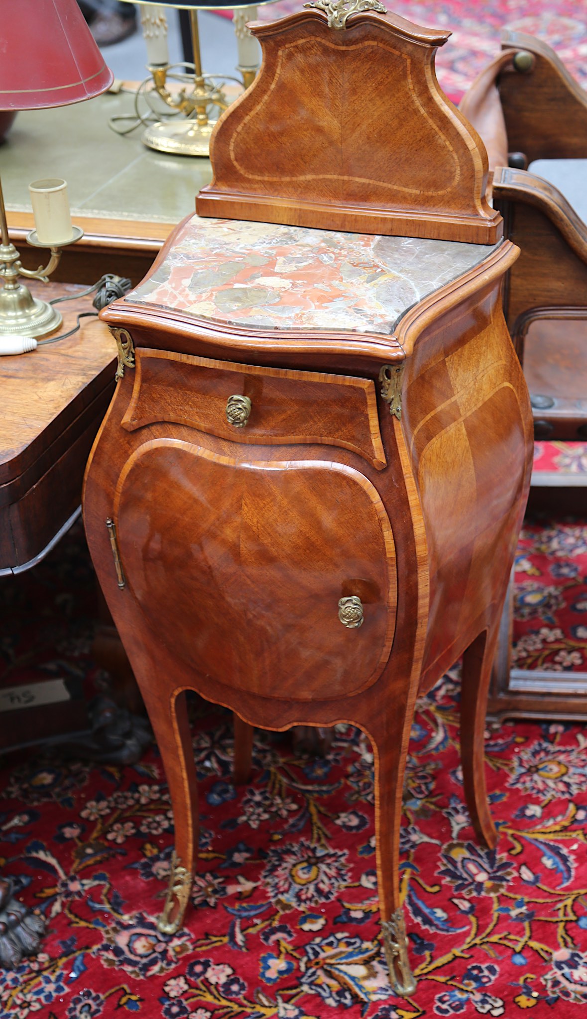 A pair of early 20th Century French, crossbanded mahogany bedside cabinets of bombe serpentine form,