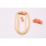 A triple strand cultured pearl necklace with a large foliate carved coral clasp, accompanied by a
