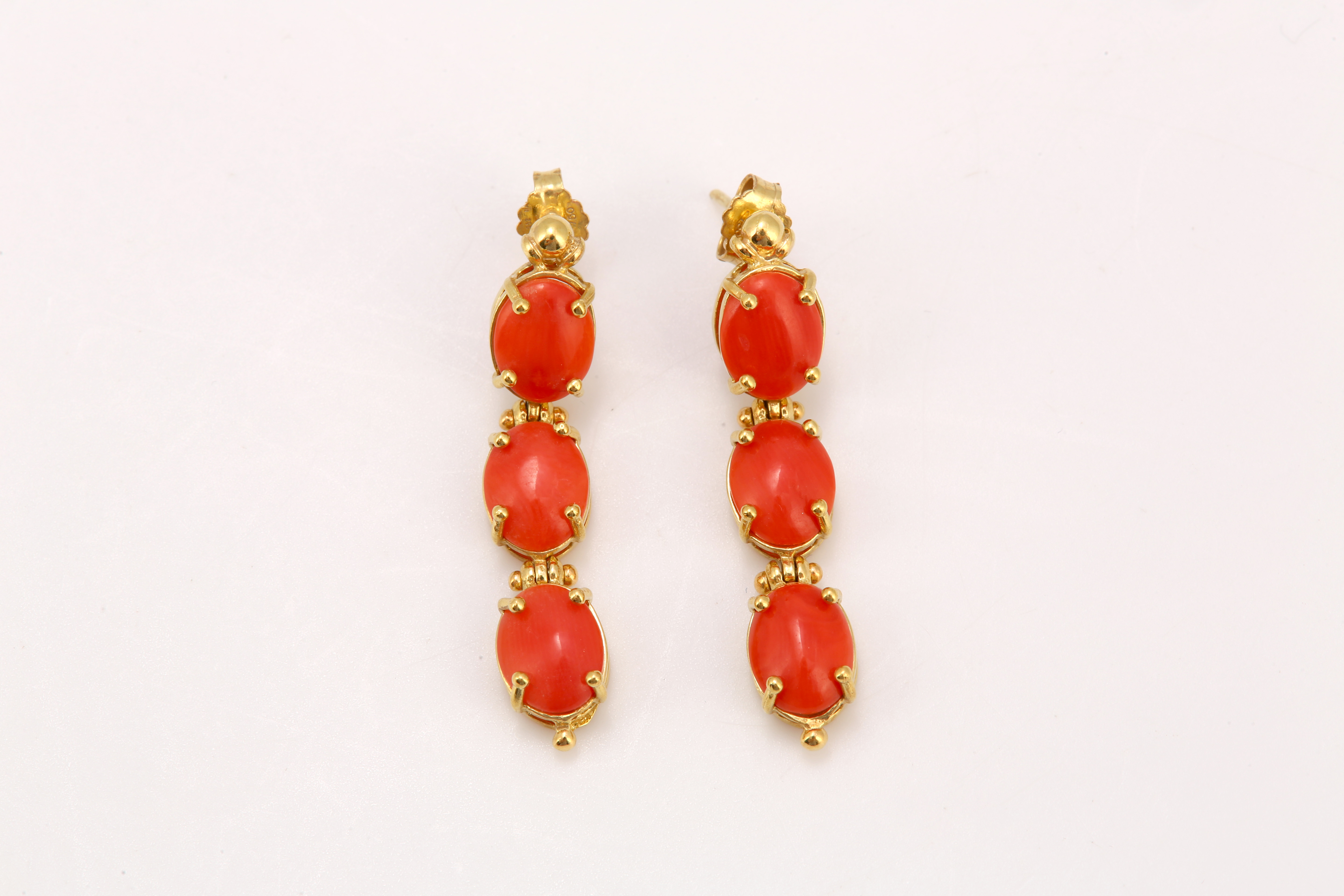 A pair of coral cabochon three-stone pendent earrings