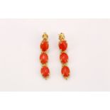 A pair of coral cabochon three-stone pendent earrings