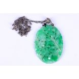A jade and diamond pendant necklace, The pierced oval carved jade pendant, suspended from a