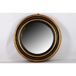 A Regency convex mirror, early 19th Century, in a moulded ebonised and parcel gilt circular frame,
