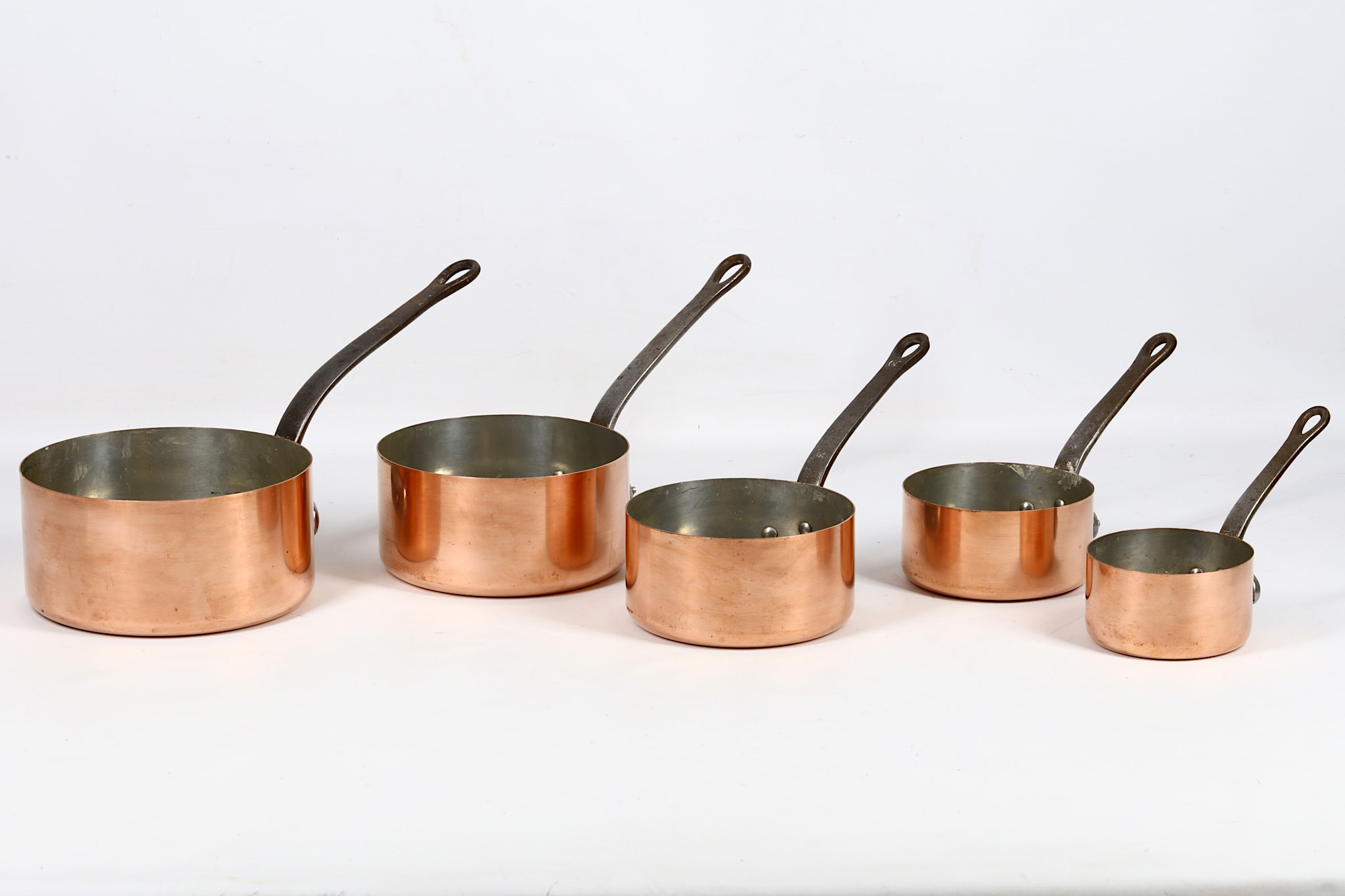 A set of 5 graduated copper saucepans with steel handles and tinned interiors (5).