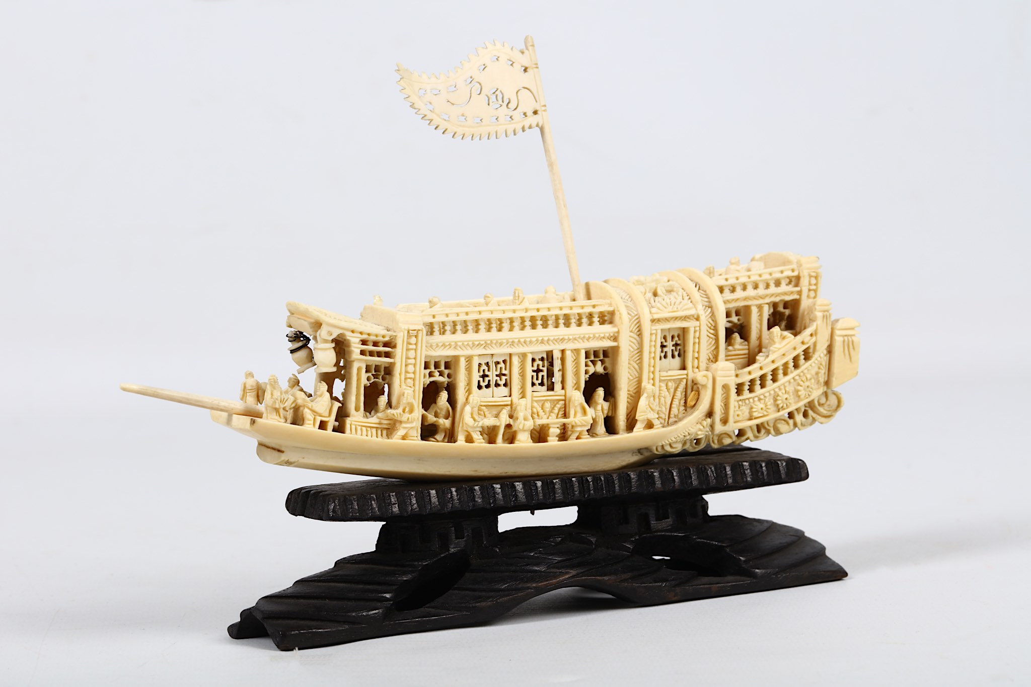 A carved ivory ceremonial barge, c.1910, having figures seated and standing, supplied on a carved