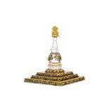 A ROCK CRYSTAL AND GILT BRONZE STUPA. 19th Century. The gilt bronze stepped base of square