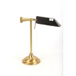 A 1950s brass desk lamp, with black enameled shade, joined to stem by articulating arm (50cm high).