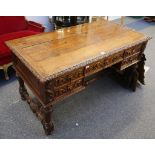 A Victorian carved oak writing table with four drawers and reeded legs, in Jacobean manner.