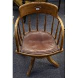 An early 20th Century ash tub frame desk chair, with turned spindle back on quadruple base.