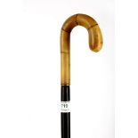 A Victorian ebonised walking stick, the shaped handle possibly rhinoceros horn with yellow metal