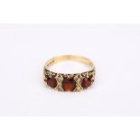 A garnet three-stone ring, Between diamond points, mounted in 9ct gold, UK hallmark, ring size O