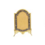 A late 19th / early 20th Century French shaped gilt bronze and enameled strut picture frame, with