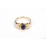A sapphire and diamond ring, The oval cabochon sapphire between brilliant-cut diamonds, stamped 585,