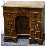 A small 18th Century feather-banded walnut kneehold desk, the quarter veneered top over seven