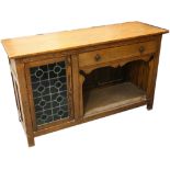 An Arts & Crafts oak sideboard enclosed by a leaded stained glass door, fitted over an open