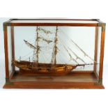 A modern hand built tall ship within a rectangular glass case,