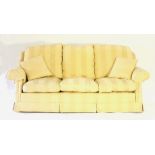 A pale yellow upholstered three-seater settee, with scroll arms and straight back,