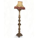 A carved gilt wood standard lamp on paw feet with shade,