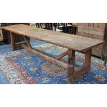 A rustic fruitwood refectory style table on square legs united by a square stretcher,