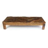 A rustic coffee table with geometric planked top on square legs,