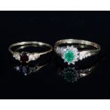 An emerald and diamond cluster ring of crossover design set with four small graduating diamonds to