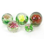 A group of five lampwork glass paperweights, each with flowerhead design,