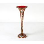 A Bohemian red glass trumpet shaped vase decorated white overlay panels of flowers,