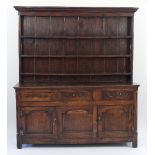 An 18th Century oak dresser with rack above a base fitted three drawers above two fielded panel