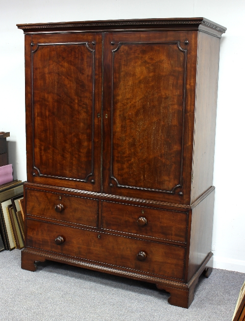 A George III mahogany linen press with dentil cornice, fitted sliding trays,