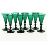 Eight green glass wine glasses with knopped stems and circular bases,