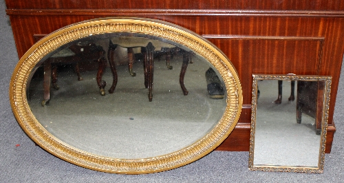 An oval wall mirror with gilded frame, 86cm wide and an oak wall mirror with carved frame,