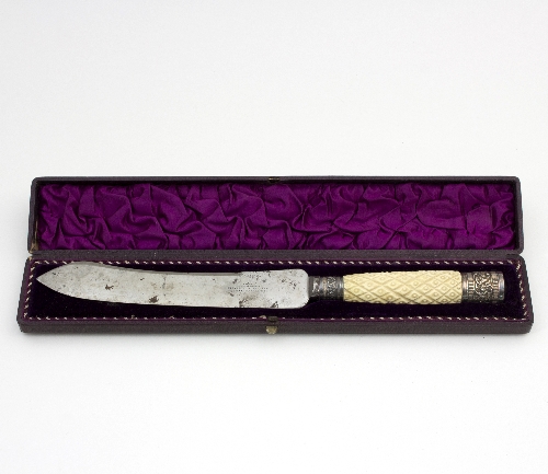 A cased bread knife with carved ivory handle