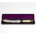 A cased bread knife with carved ivory handle