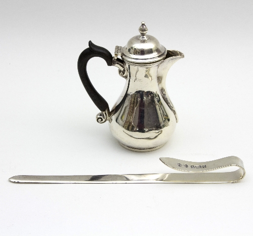 A small silver hot milk pot, London 1911, with ribbed spout and ebonised handle,