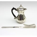 A small silver hot milk pot, London 1911, with ribbed spout and ebonised handle,