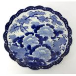 A Japanese blue and white charger, decorated flowering branches and with a lobed border,