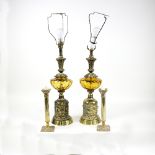 A pair of brass and amber glass table lamps, each cast in relief with mask heads and fruiting vines,