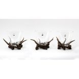 A set of three faux antler centrepieces, each supporting a clear glass bowl,
